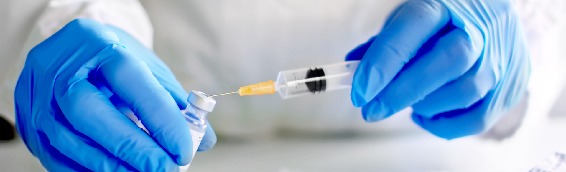 pharmacist prepping syringe and vaccine for a patient