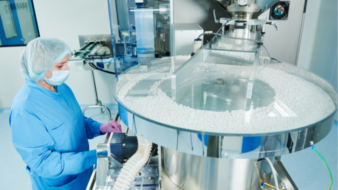 Pharmaceutical worker operates tablet blister packaging machine