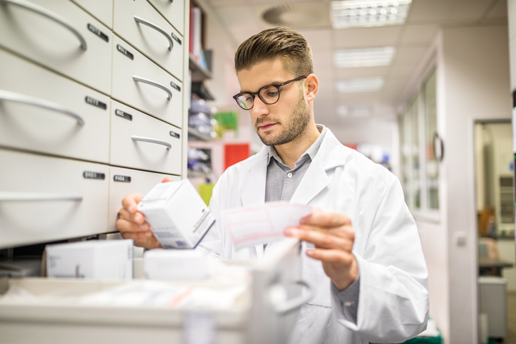 male pharmacist looking at medications