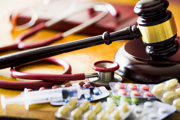 judges gavel with stethoscope and pills