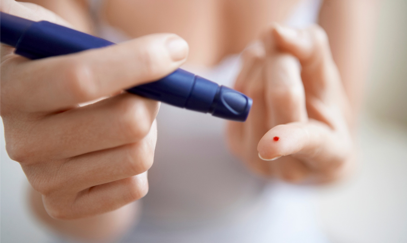 woman using a lancelet on her finger