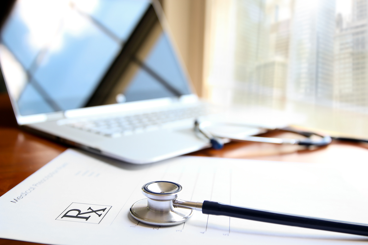 open laptop on top of prescription pad and stethoscope