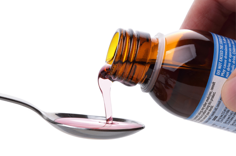 cough syrup being poured on a spoon