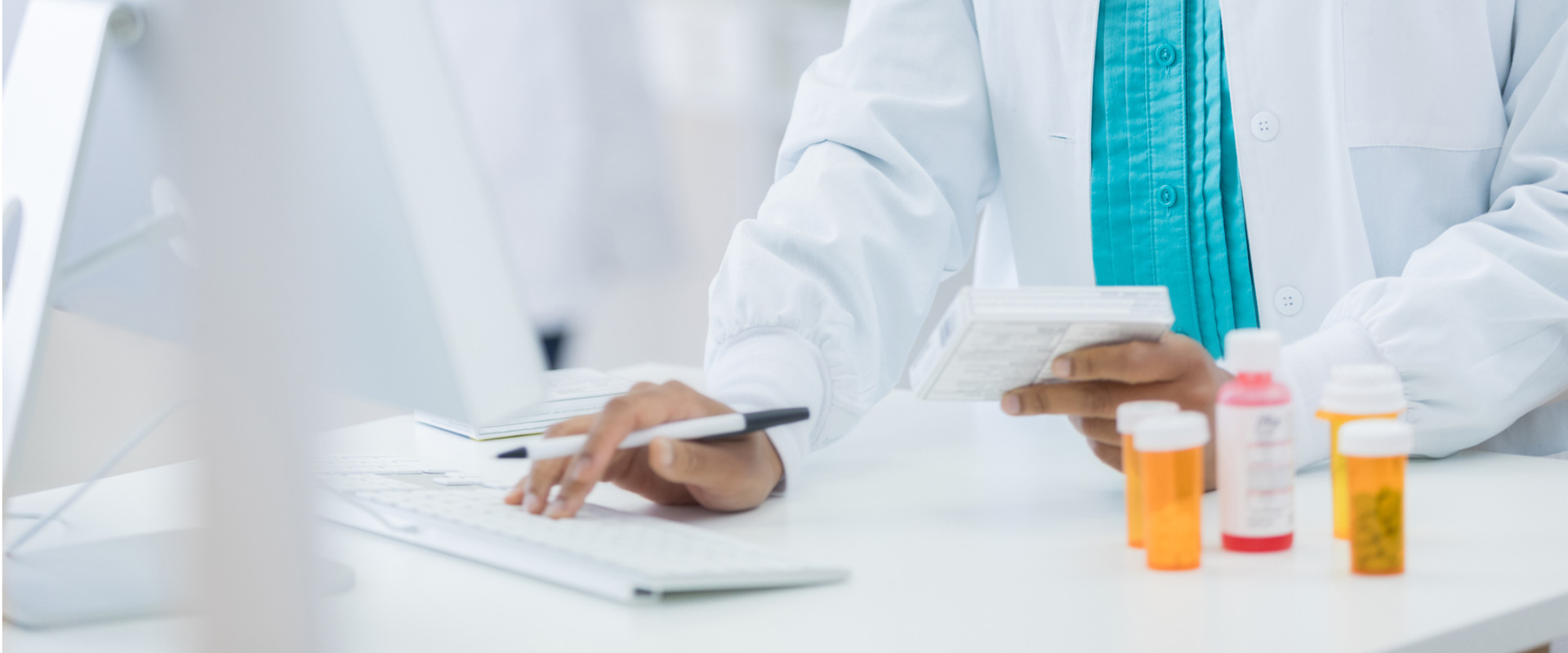retail pharmacist working on a computer and filling a prescription