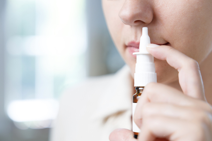 close up of a woman using nasal spray