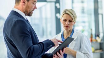 Woman in lab coat and man in suit discussing findings